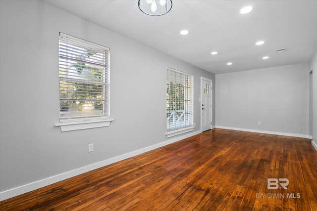 spare room featuring plenty of natural light and dark hardwood / wood-style flooring