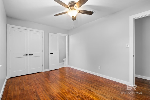 unfurnished bedroom featuring ensuite bath, ceiling fan, a closet, and dark hardwood / wood-style floors