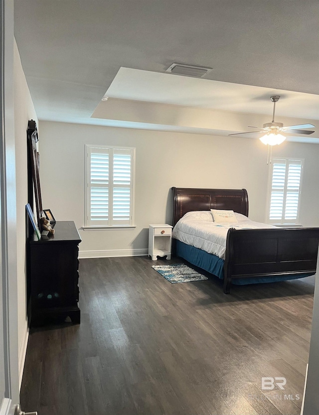 bedroom featuring dark wood-style floors, visible vents, baseboards, and a ceiling fan