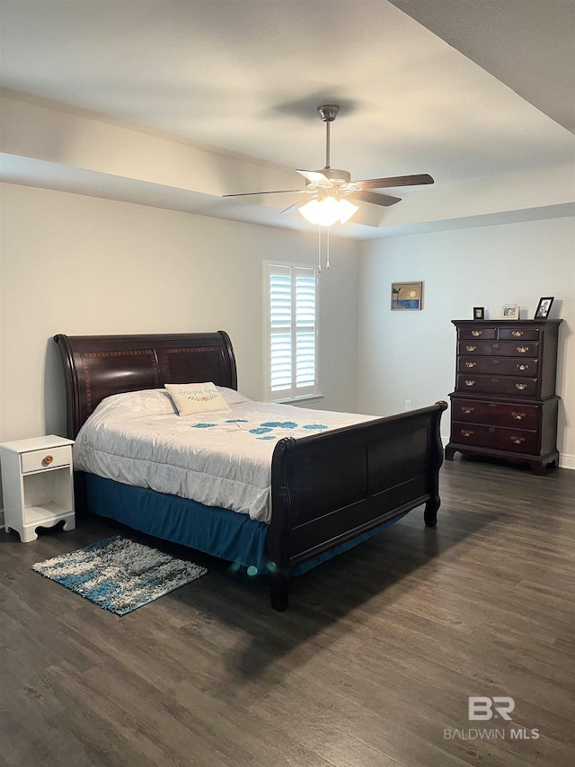 bedroom featuring a tray ceiling, ceiling fan, and wood finished floors