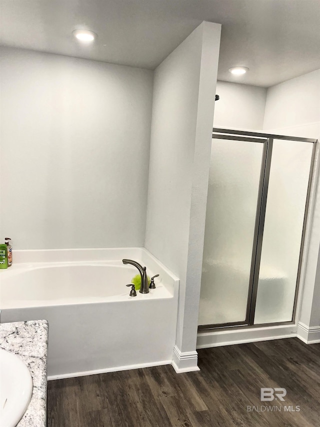 full bathroom featuring a stall shower, wood finished floors, a bath, and recessed lighting