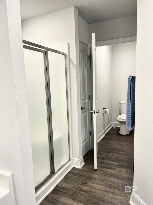 bathroom featuring baseboards, toilet, wood finished floors, and a shower stall