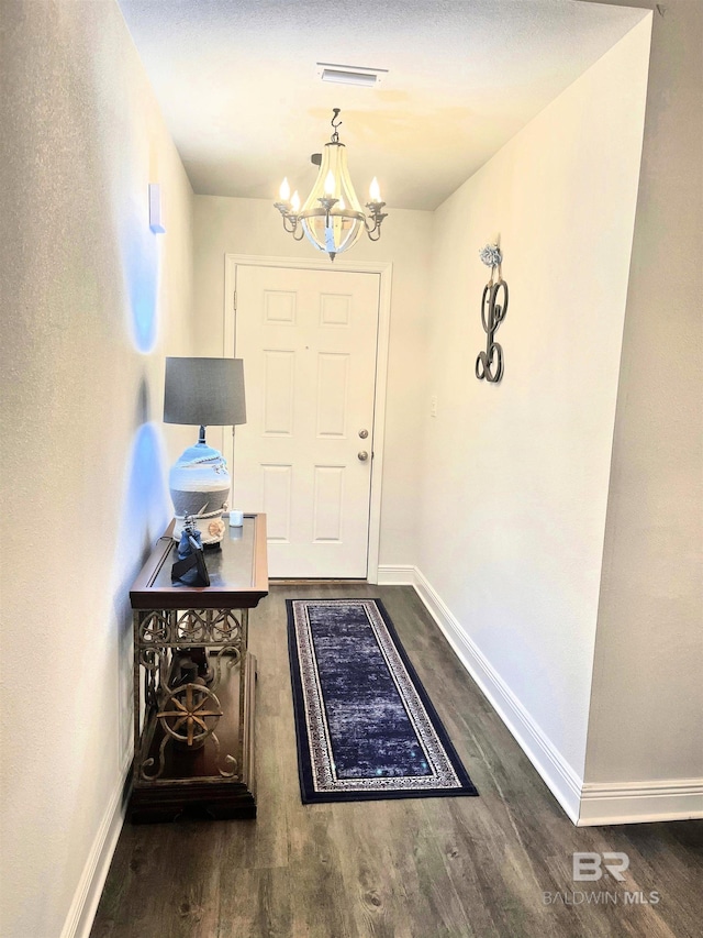 entryway with a notable chandelier, baseboards, and wood finished floors