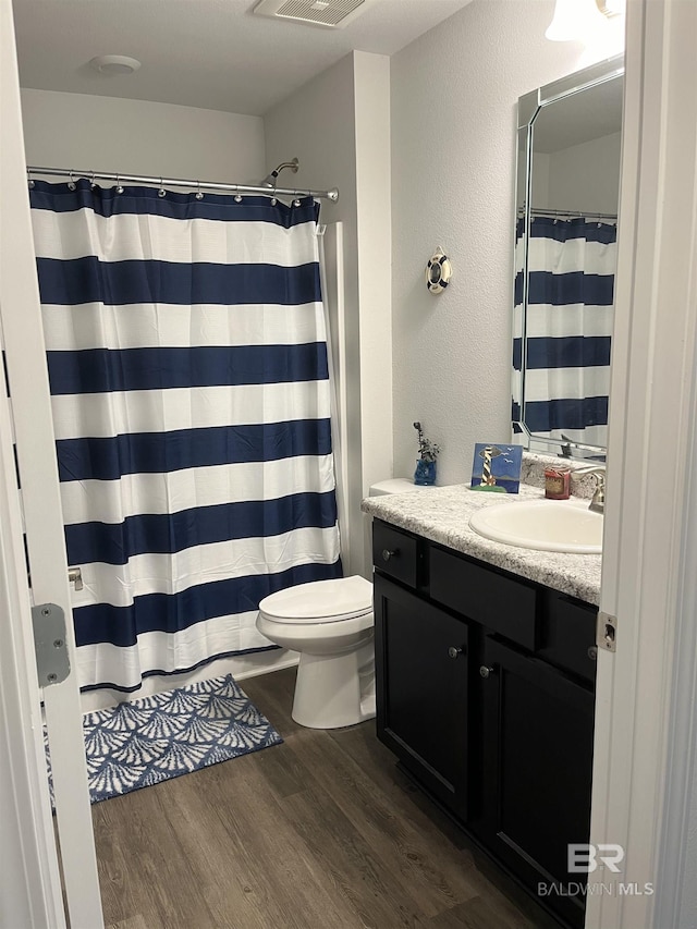 full bath with visible vents, toilet, curtained shower, wood finished floors, and vanity