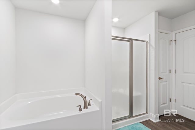 bathroom featuring a bath, a stall shower, and wood finished floors