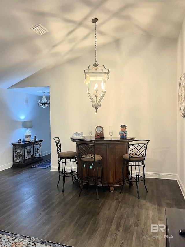 dining space featuring vaulted ceiling, a dry bar, dark wood-style floors, and visible vents