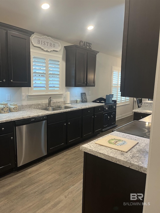 kitchen featuring a sink, stainless steel dishwasher, dark cabinetry, light wood finished floors, and black electric stovetop