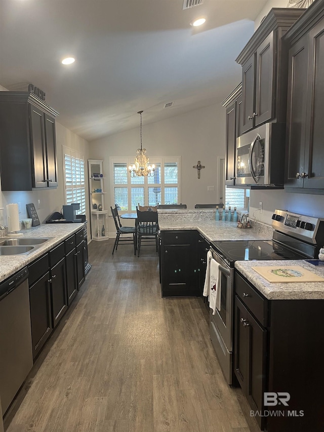 kitchen featuring a sink, wood finished floors, stainless steel appliances, light countertops, and lofted ceiling