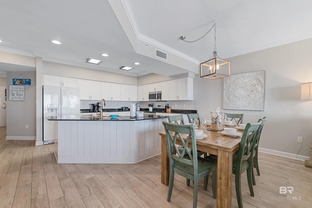 dining area with sink, crown molding, and light hardwood / wood-style floors