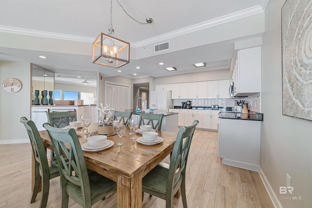 dining space featuring an inviting chandelier, ornamental molding, and light hardwood / wood-style flooring