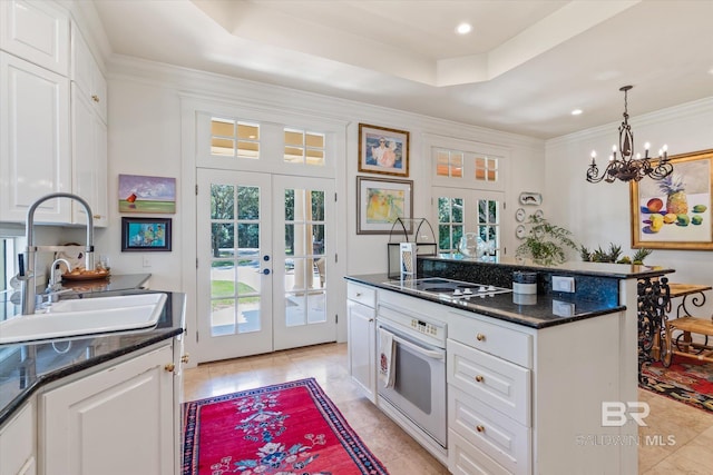 kitchen featuring oven, a tray ceiling, french doors, white cabinetry, and light tile patterned floors