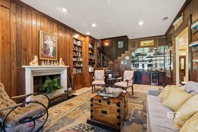 living room featuring built in features, wooden walls, crown molding, and beverage cooler