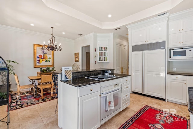 kitchen with light tile patterned floors, a raised ceiling, built in appliances, and white cabinets