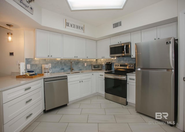 kitchen with white cabinetry, appliances with stainless steel finishes, sink, and backsplash