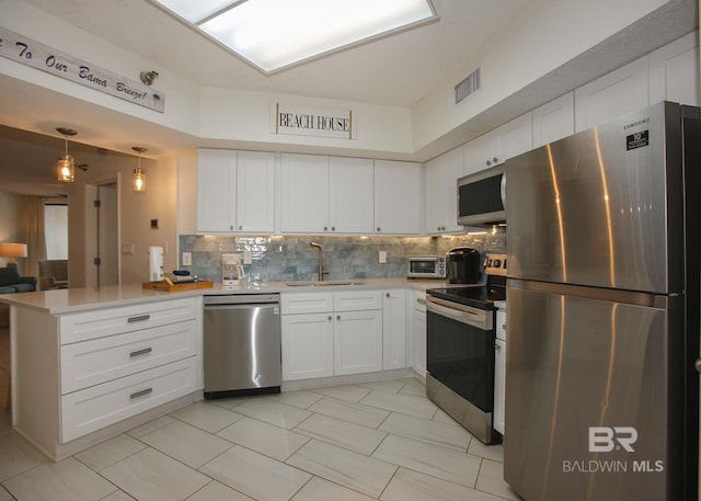 kitchen with sink, appliances with stainless steel finishes, white cabinetry, tasteful backsplash, and kitchen peninsula