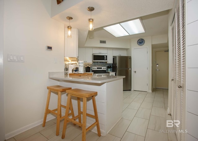 kitchen with white cabinetry, stainless steel appliances, decorative light fixtures, and kitchen peninsula