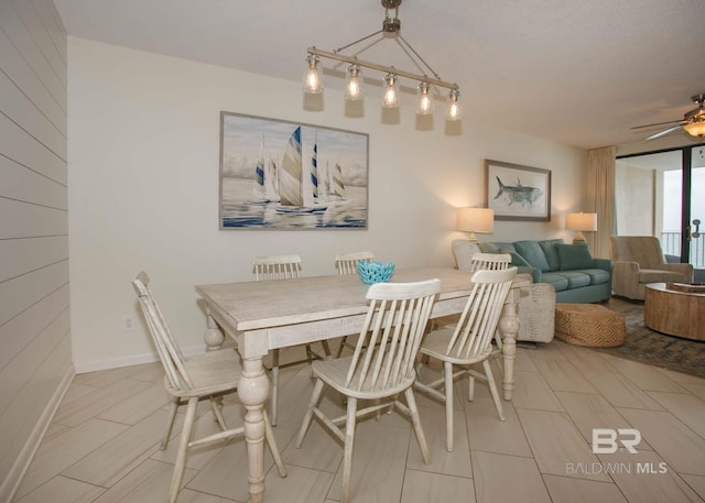 dining room with ceiling fan and wood walls