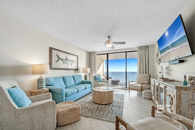 living room with ceiling fan, a textured ceiling, and a wall of windows