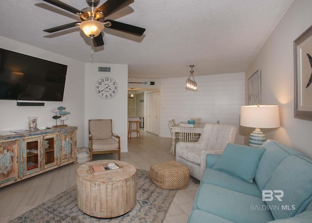 living room featuring ceiling fan and a textured ceiling