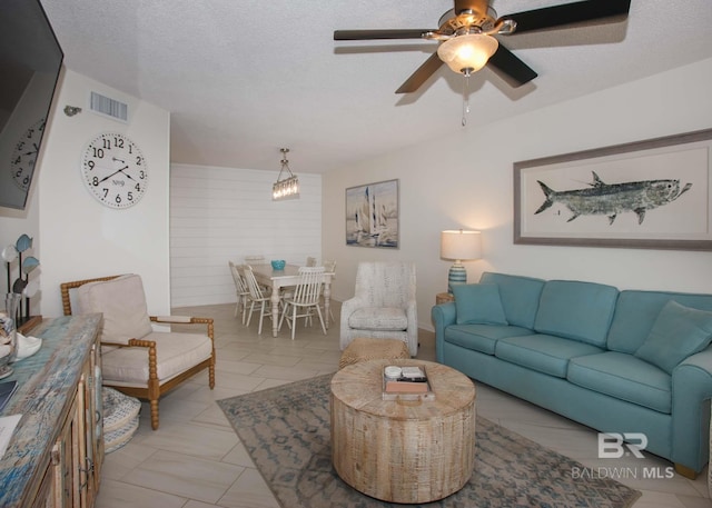 living room featuring ceiling fan and a textured ceiling