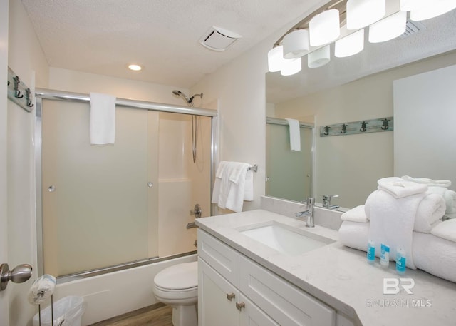 full bathroom with toilet, bath / shower combo with glass door, a textured ceiling, vanity, and hardwood / wood-style flooring