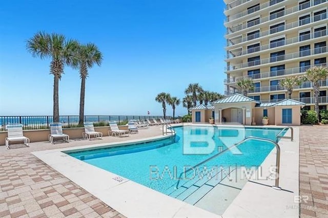 view of pool with a water view and a patio area