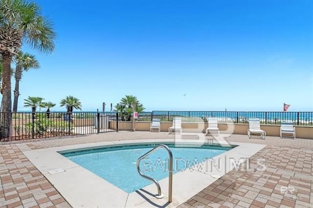 view of swimming pool featuring a water view and a patio