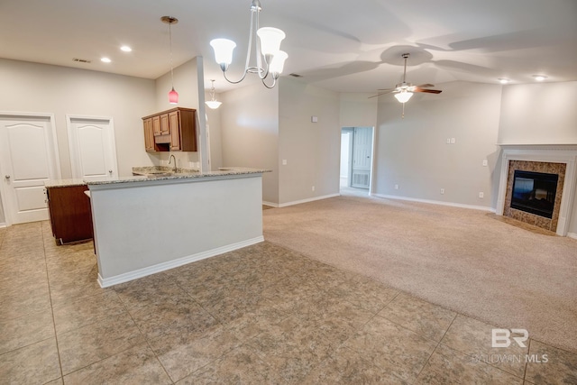 kitchen featuring light carpet, ceiling fan with notable chandelier, light stone countertops, a fireplace, and decorative light fixtures