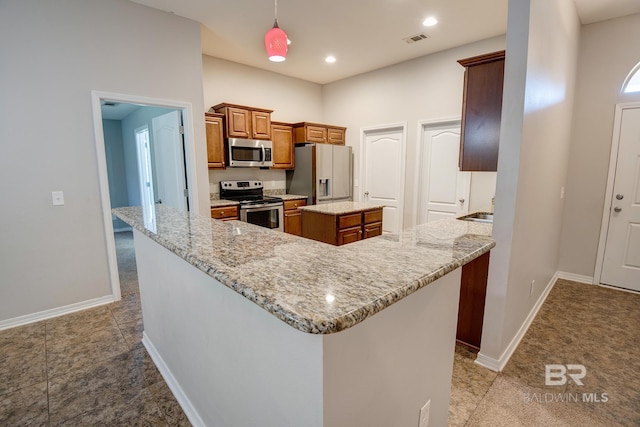 kitchen with light stone countertops, sink, a center island, stainless steel appliances, and decorative light fixtures