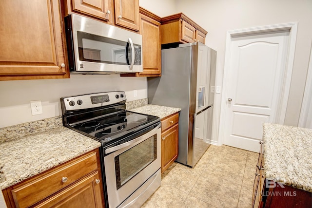 kitchen featuring light stone countertops, light tile patterned floors, and stainless steel appliances