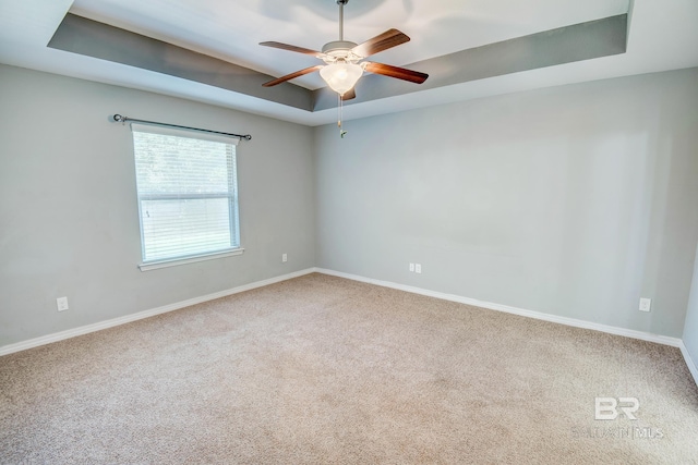 carpeted spare room featuring ceiling fan and a tray ceiling