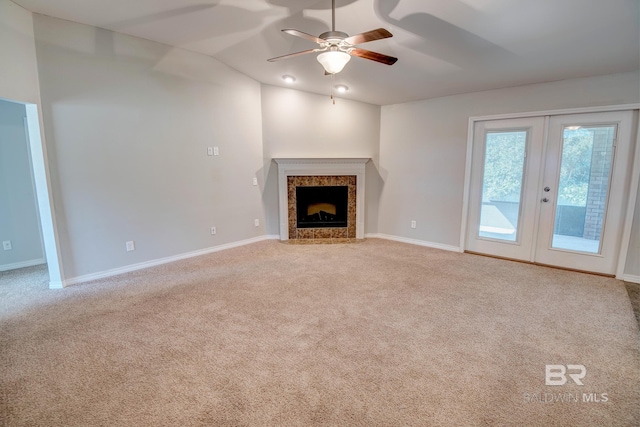 unfurnished living room featuring a fireplace, light carpet, french doors, and ceiling fan