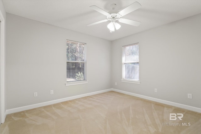 spare room featuring baseboards, light carpet, and a ceiling fan