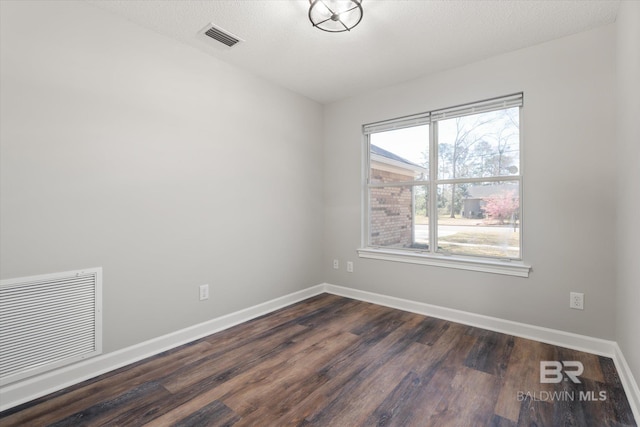 unfurnished room featuring visible vents, baseboards, dark wood-type flooring, and a textured ceiling