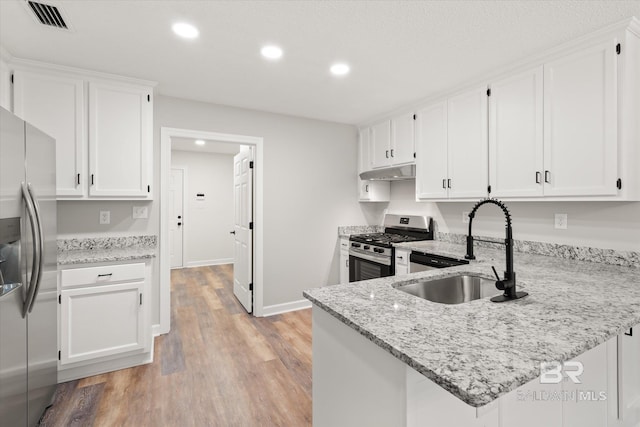 kitchen featuring visible vents, under cabinet range hood, white cabinets, stainless steel appliances, and a sink