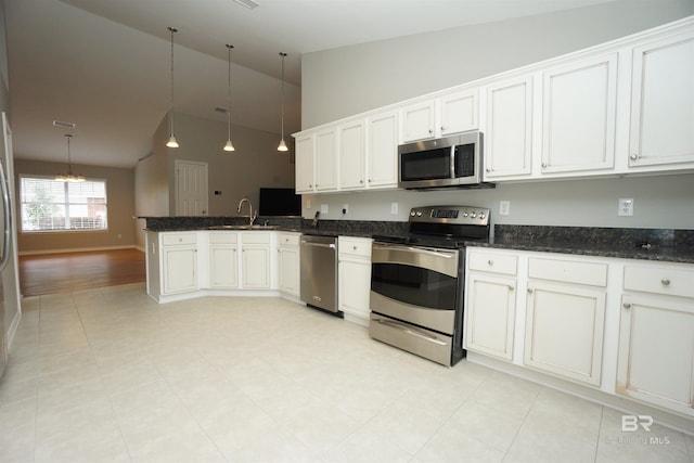 kitchen featuring pendant lighting, kitchen peninsula, sink, appliances with stainless steel finishes, and white cabinetry