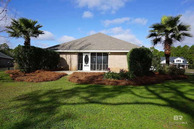 rear view of property with a lawn and a sunroom