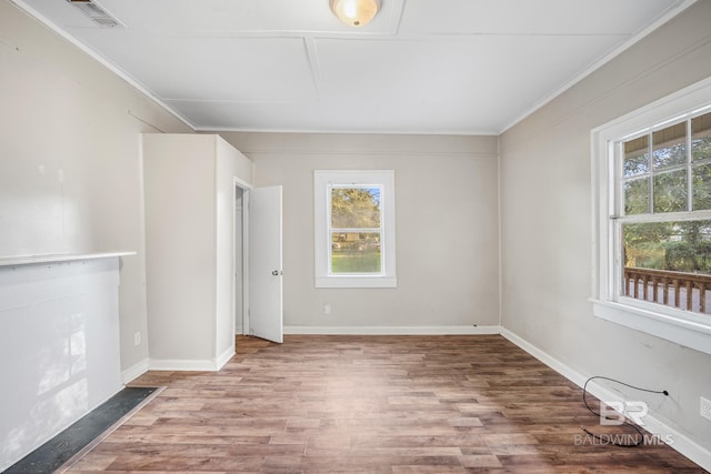 unfurnished room featuring hardwood / wood-style flooring, crown molding, and a healthy amount of sunlight