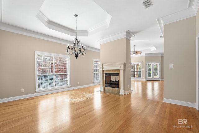 unfurnished living room featuring a multi sided fireplace, light hardwood / wood-style flooring, and a tray ceiling