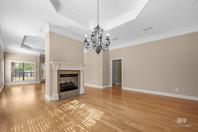 unfurnished living room with a multi sided fireplace, a tray ceiling, light hardwood / wood-style flooring, and ornamental molding