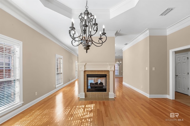 unfurnished living room featuring a multi sided fireplace, light wood-type flooring, a chandelier, and crown molding