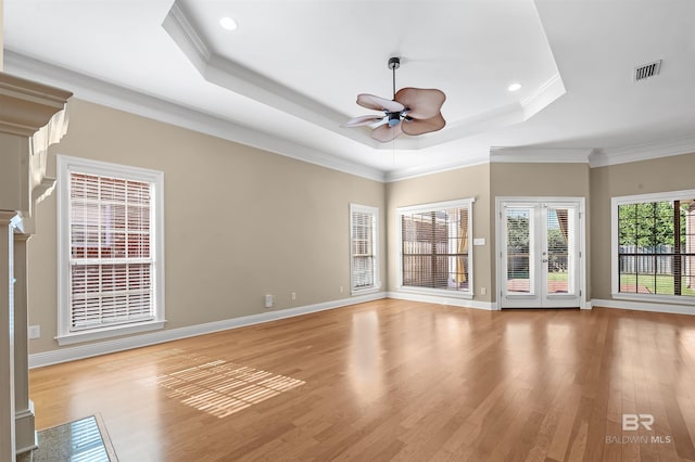 spare room featuring a raised ceiling, light hardwood / wood-style flooring, ceiling fan, and crown molding