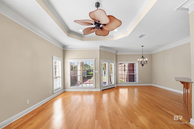 interior space with a raised ceiling, ceiling fan with notable chandelier, light hardwood / wood-style flooring, and ornamental molding