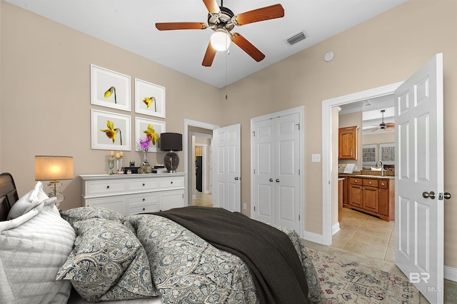 bedroom featuring ceiling fan, sink, light tile patterned floors, and ensuite bathroom