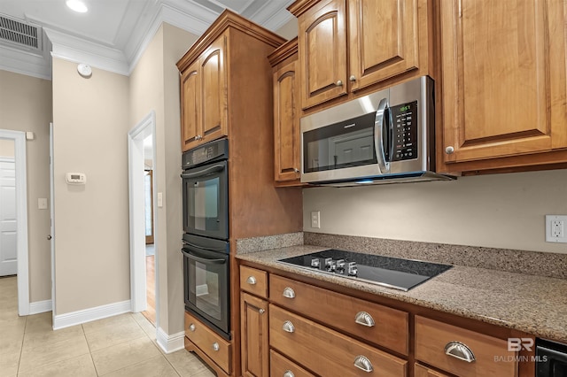 kitchen with light tile patterned flooring, light stone counters, ornamental molding, and black appliances