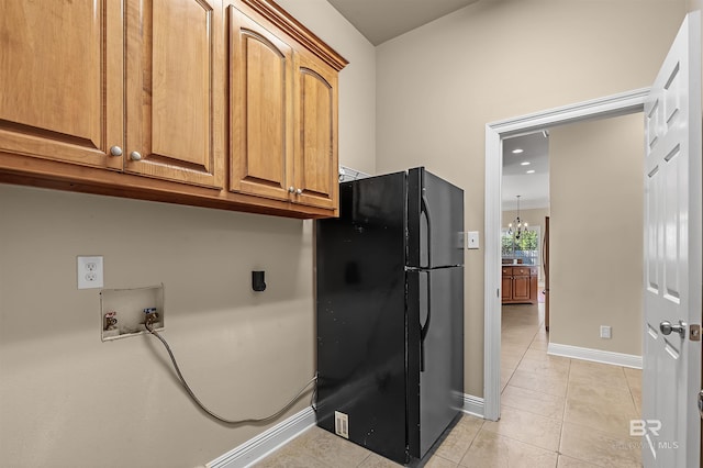 kitchen featuring black refrigerator, light tile patterned floors, and a chandelier