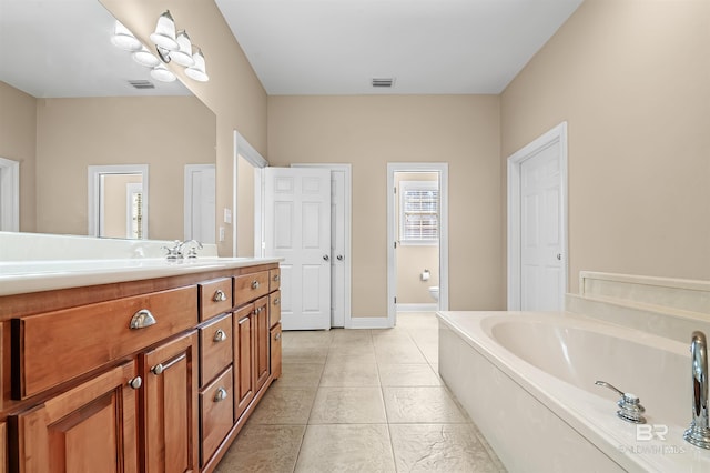 bathroom featuring a washtub, tile patterned floors, vanity, and toilet