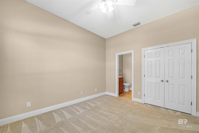 unfurnished bedroom featuring ceiling fan, ensuite bathroom, lofted ceiling, light carpet, and a closet