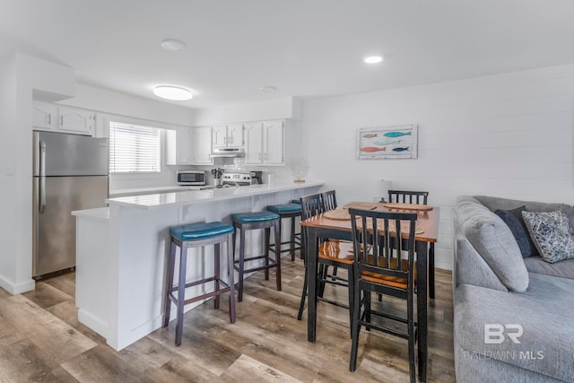 kitchen featuring stainless steel appliances, white cabinets, a kitchen breakfast bar, and kitchen peninsula