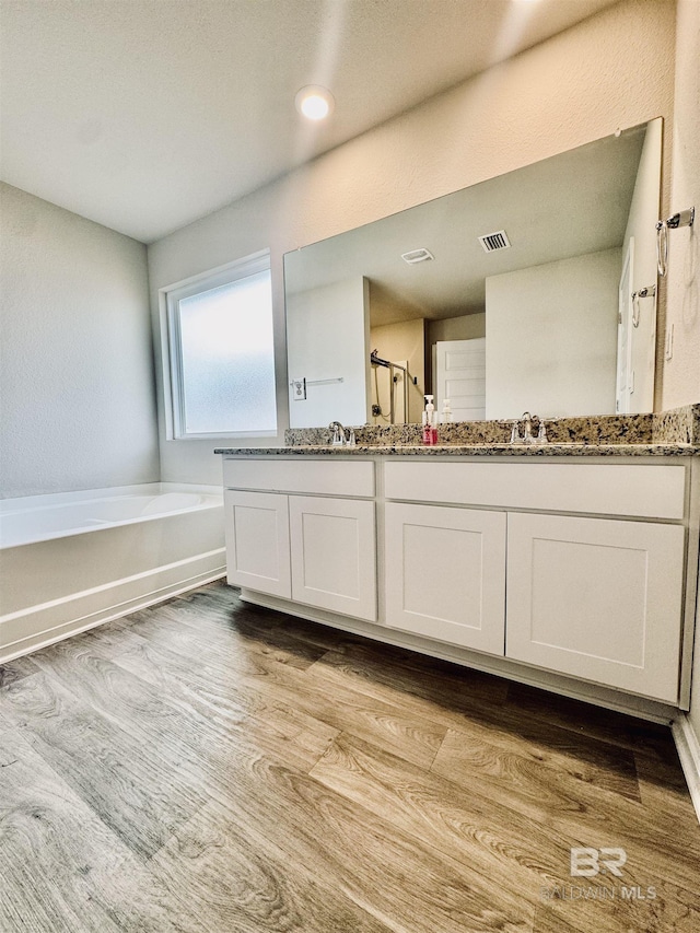 bathroom with vanity, wood-type flooring, and a bathtub